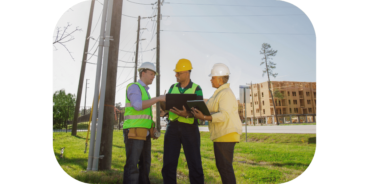Three people with hard hats discussing a plan