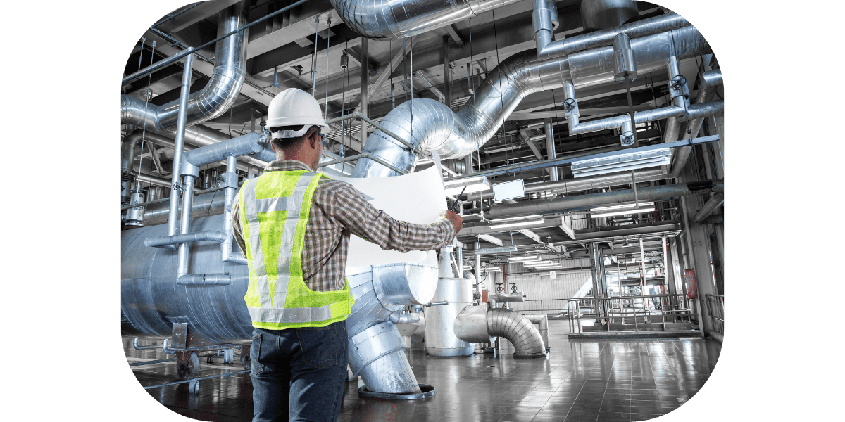 Worker in a plant wearing a hard hat and vest looking at a schematic. 